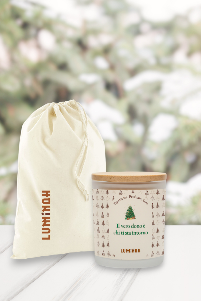 Candela Luminah Aghi di Pino con sacchetto in tessuto, fotografata su sfondo invernale sfocato