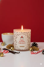 Candela artigianale Luminah Mocaccino di Natale in vetro satinato, accesa su sfondo rosso con decorazioni natalizie, caffè e bastoncini di zucchero.”